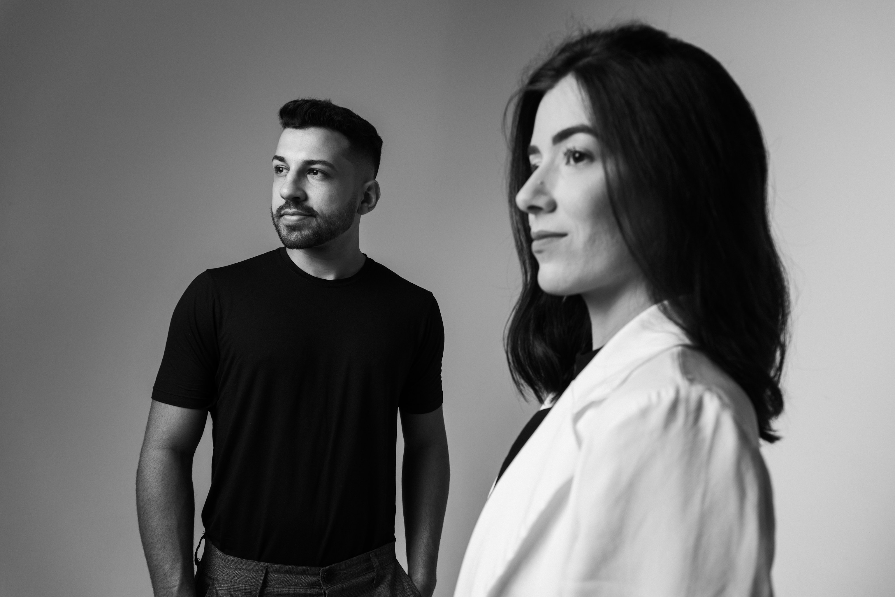 A blurry black and white photo with two people, a woman in the foreground and a man in the background, both looking off to the side.